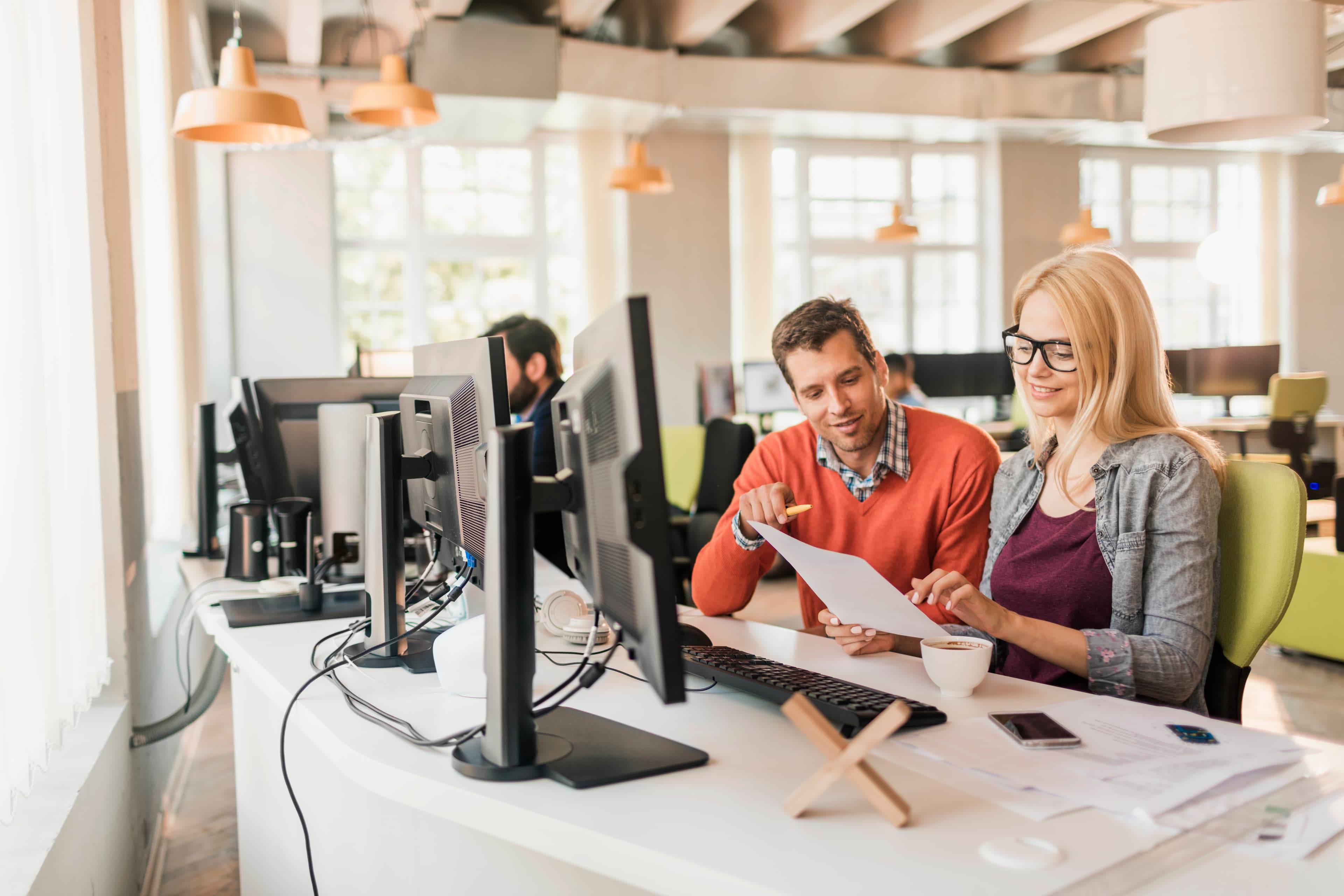 Young Caucasian man and woman going over paperwork in a startup company office