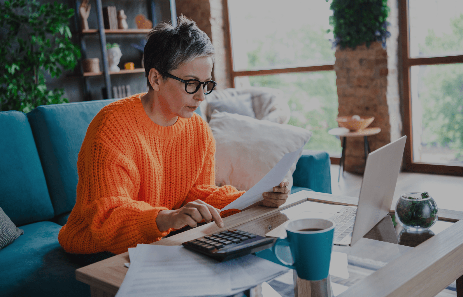 Woman in orange sweater using calculator